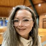 Pictured is Arienne Gorlach, LH Agenda's Community Coach. She wears glasses and her hair out, and is smiling at the camera.