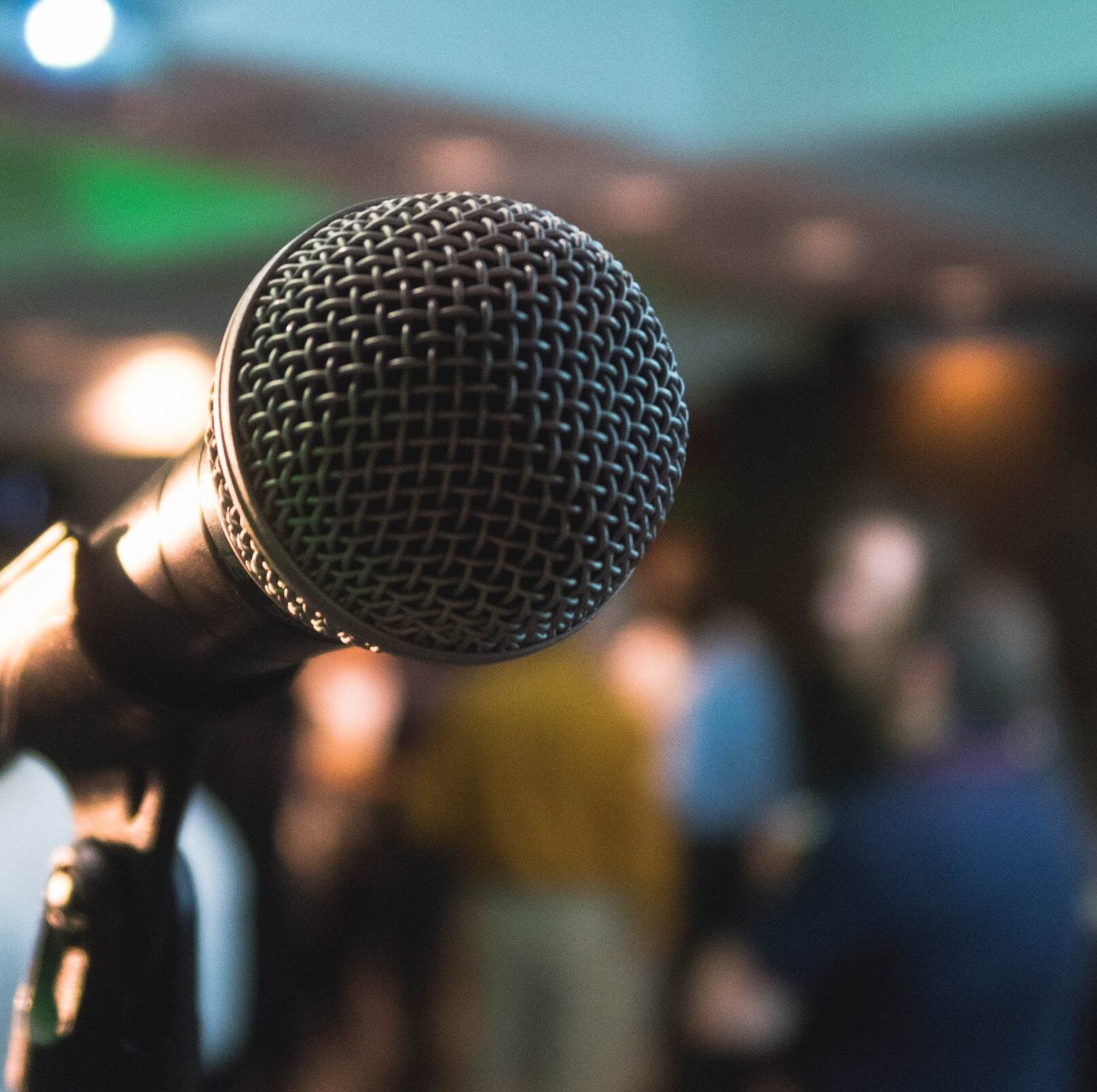 A microphone before a crowd of people, waiting for a speech on personal brand.