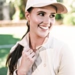 Miss International Australia, Selina McCloskey smiles, wearing a Skye Melody jacket and baseball cap.